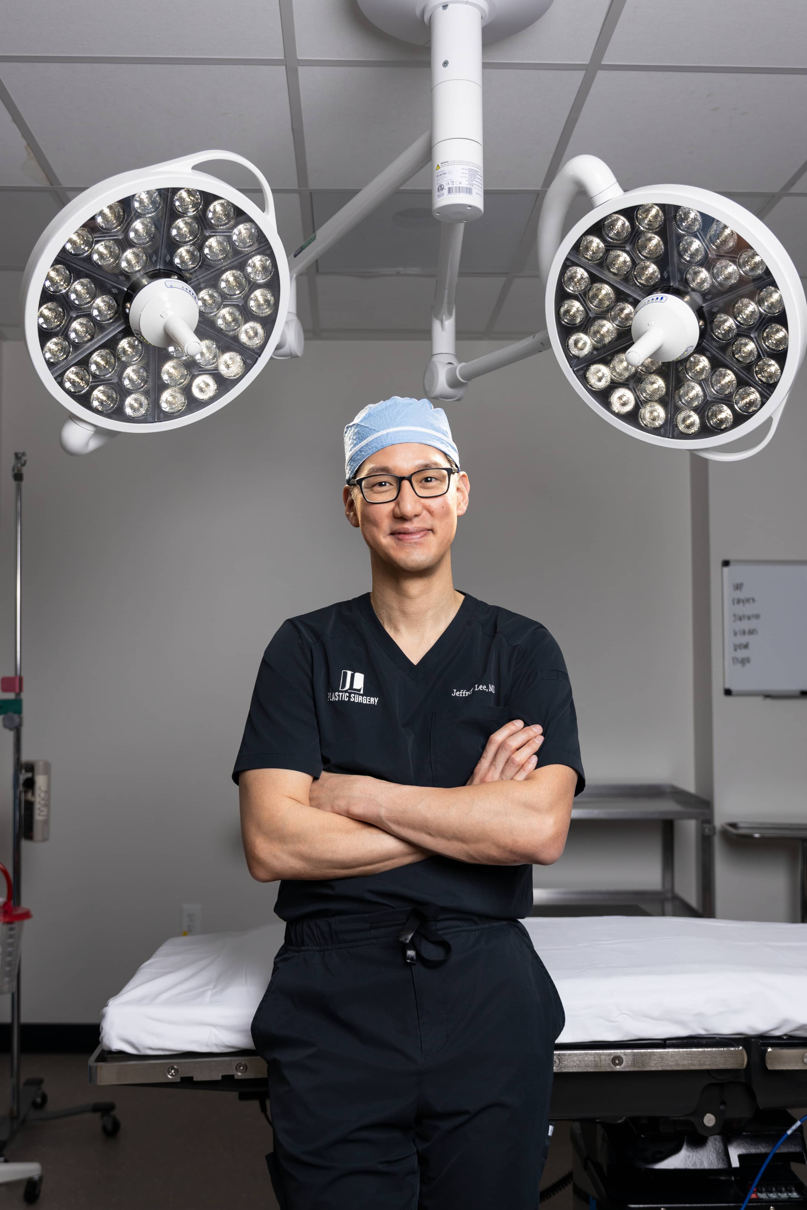 Dr. Jeffrey Lee in surgical scrubs with his arms folded, standing in an operating room