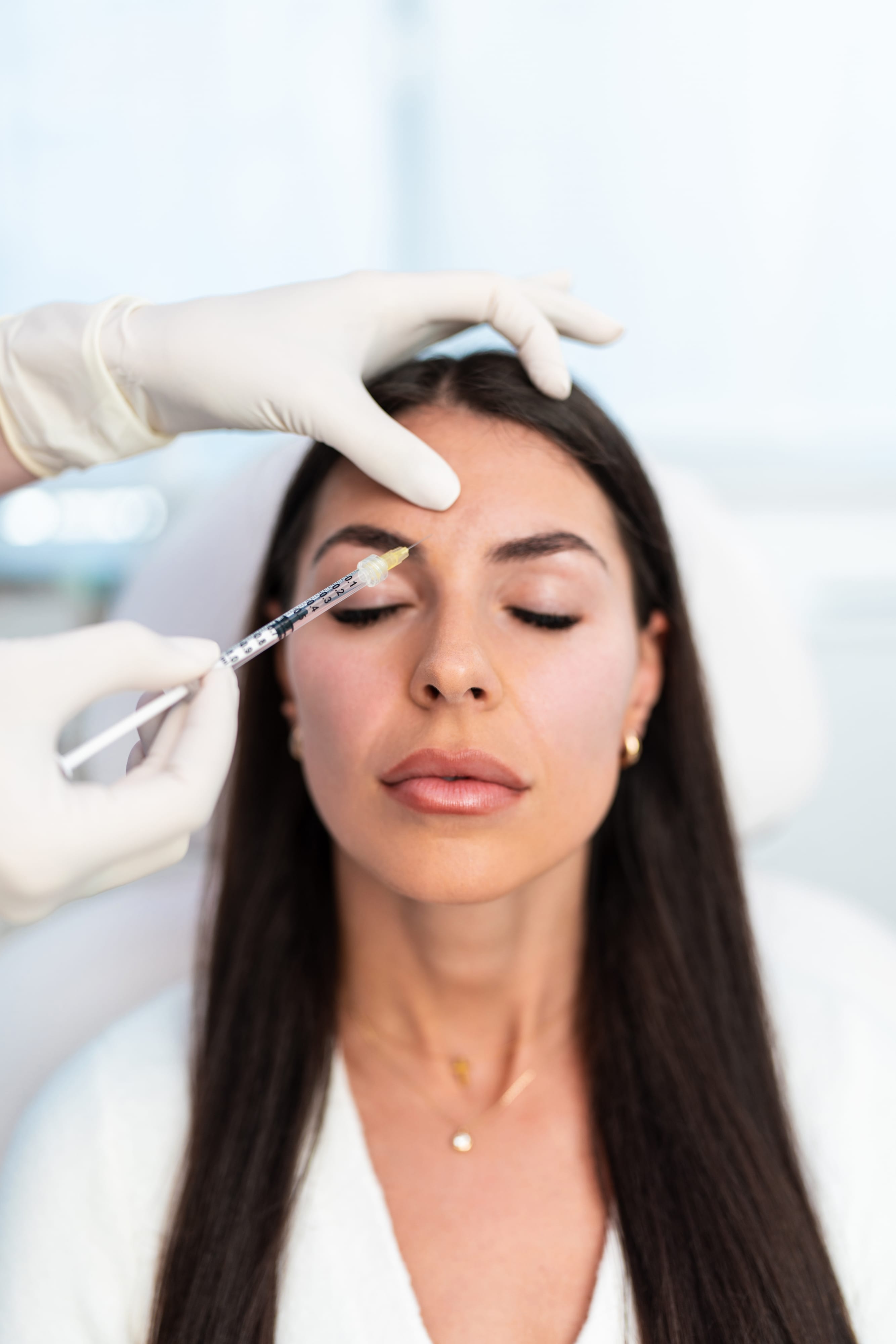 Gloved hands administering a facial injection during a one-on-one Botox and dermal filler training session